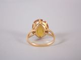 a close up of a yellow stone ring on a white surface