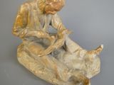 une statue représentant un homme assis sur un rocher avec un chien