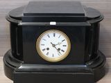 a black clock sitting on top of a wooden table