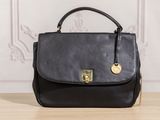 a black handbag sitting on top of a wooden table