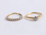 two gold rings with diamonds on them on a white surface