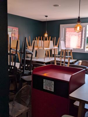Des tables et des chaises sont alignées dans une pièce où est accrochée une affiche au mur.