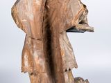 wooden statue of a man holding a tray with a dog on it