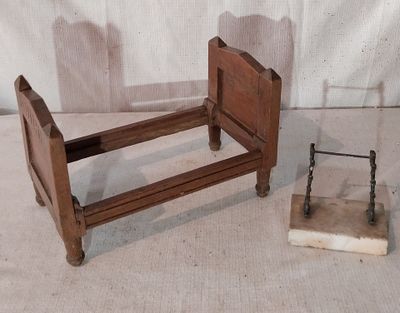 un petit lit avec un cadre en bois, à côté d'un bloc de pierre