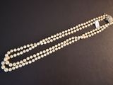 a close up of a pearl necklace on a black surface