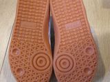 pair of orange rubber shoes on a wooden floor with a white background