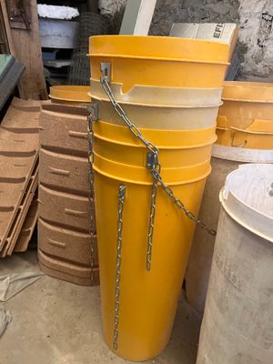 un grand seau jaune posé à côté d'une pile d'autres seaux