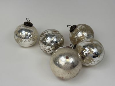 quatre boules de Noël en verre argenté posées sur un fond blanc
