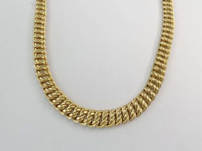 gros plan d'un collier à chaîne en or sur une surface blanche