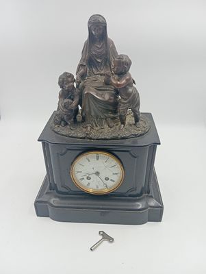 statue représentant une femme avec deux enfants et une horloge posée sur une table