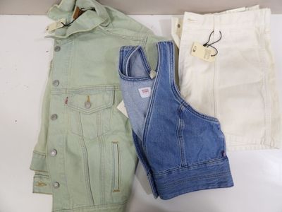 two pairs of jeans and a jacket sitting on a table