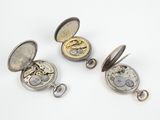 three different types of pocket watches on a white surface