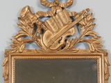 a mirror with a gold frame with a musical instrument on it