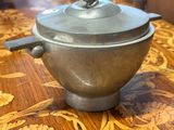a silver pot sitting on a wooden table with a lid