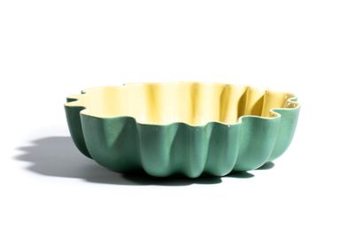 un bol vert et jaune posé sur une surface blanche