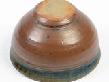 a brown and blue bowl sitting on a white surface