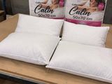 trois oreillers posés sur une table, avec des cartons d'oreillers en arrière-plan