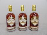 trois bouteilles d'alcool posées les unes à côté des autres sur une table