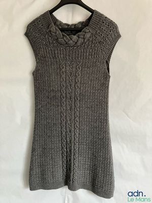 un pull gris pour femme, suspendu à un cintre posé sur un lit