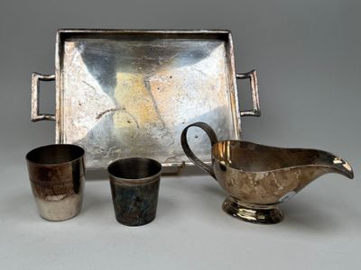 un plateau en argent sur lequel se trouvent des tasses en argent et une soucoupe en argent