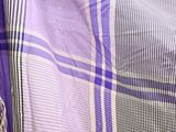 a purple and white plaid blanket on a bed