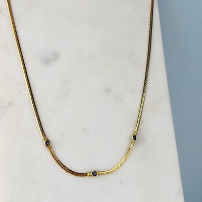 un gros plan d'un collier posé sur une surface en marbre, sur fond bleu