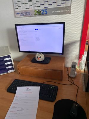 a desk with a monitor, keyboard, mouse and other items on it