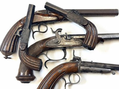 Plusieurs vieilles armes à feu sont alignées sur une surface blanche