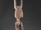 une sculpture en bois représentant un homme tenant un oiseau sur la tête