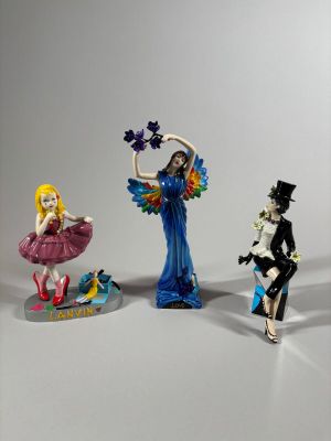 trois figurines représentant une femme en robe et un homme au haut-de-forme