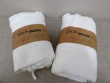 two white towels sitting on top of a couch next to each other