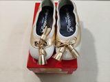 pair of white and gold shoes with bows on top of a red box