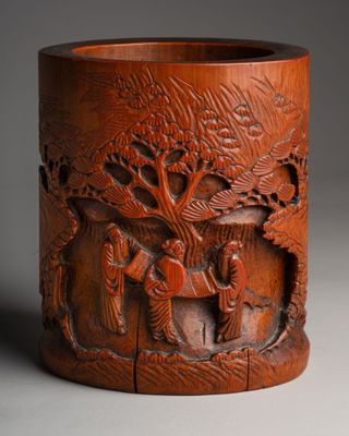 une image représentant un vase en bois orné de sculptures représentant des personnages et des arbres