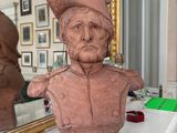 a bust of a man sitting on a table next to a mirror