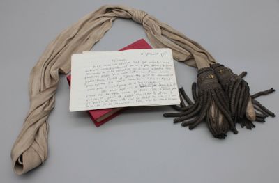 un bout de papier sur lequel il y a quelque chose d'écrit, à côté d'une écharpe