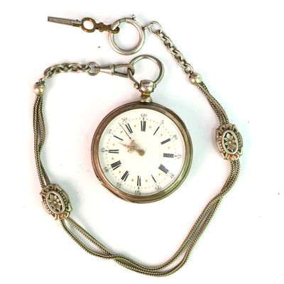 une montre de poche attachée à une chaîne, posée sur une surface blanche