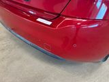 the rear end of a red car with a sticker on it ' s bumper