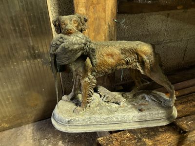 une statue représentant un chien tenant un oiseau dans la gueule