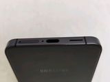 the back of a black samsung phone sitting on top of a white table