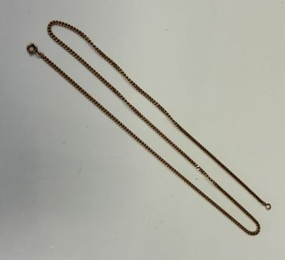 un collier en or muni d'une chaîne, posé sur une surface blanche