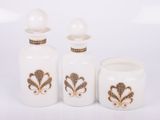 three white glass bottles with gold designs on them on a white surface