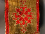 a small red and gold book on a table next to a candle