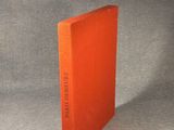an orange book sitting on top of a table next to a gray wall