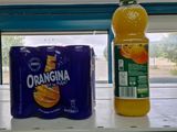 bottles of orange juice and orange juice sit on a shelf in a store