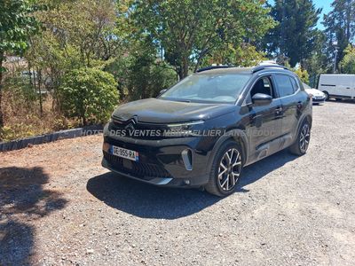 une voiture noire garée sur un parking près de quelques arbres