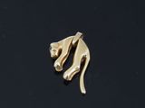 a close up of a gold cat broochle on a black surface