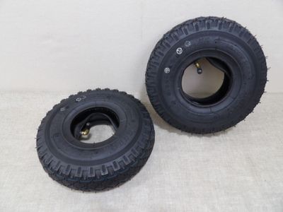 Deux pneus noirs sont posés l'un à côté de l'autre sur une surface blanche