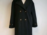 a black coat on a mannequin stand on a white wall