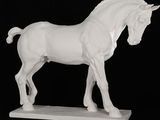 une statue blanche représentant un cheval sur fond noir