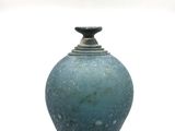 un vase bleu posé sur une surface blanche